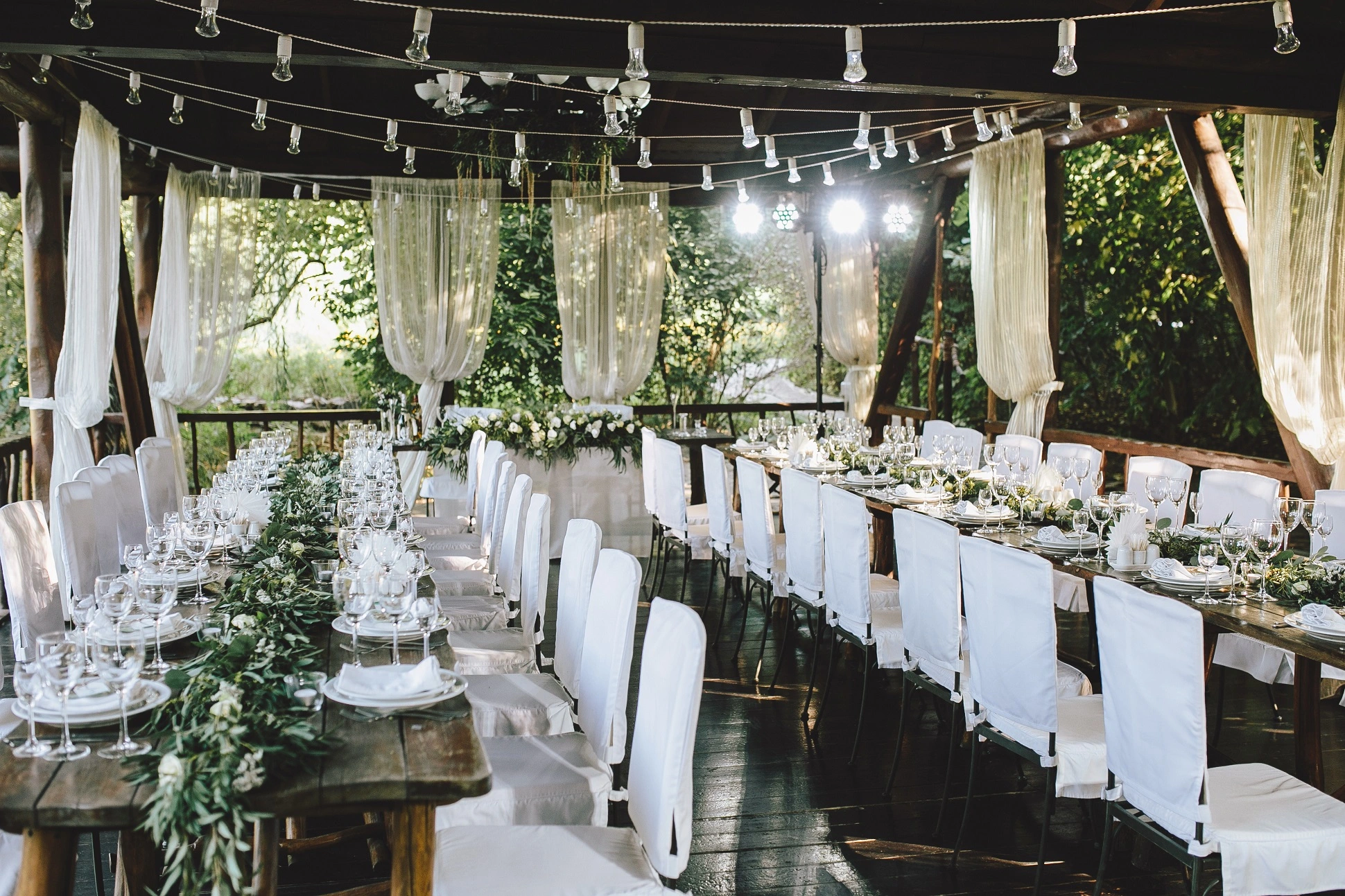 A low and distance view of the alter from the aisle, flanked by white wooden chairs.