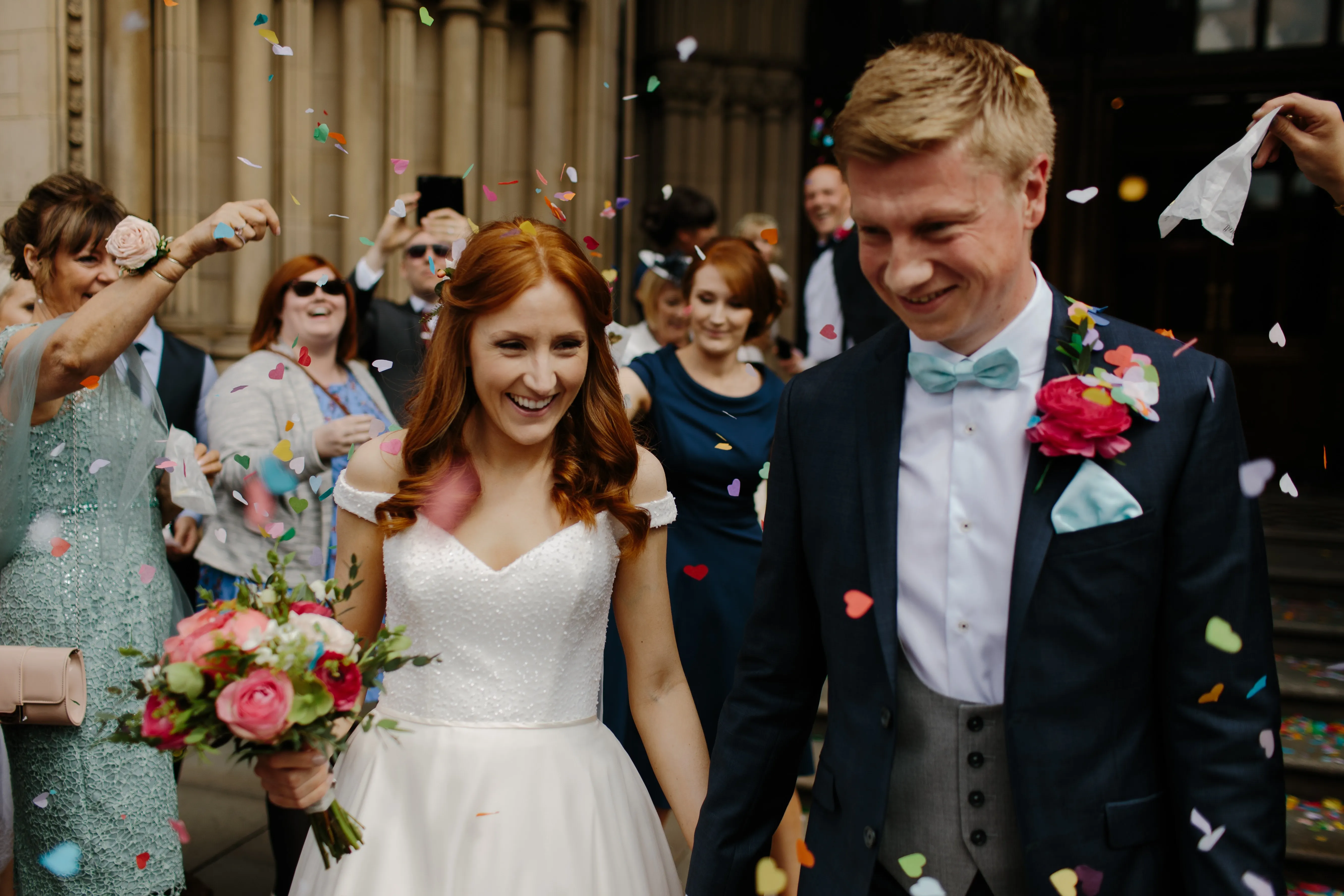 A bride and groom happily being showered with confetti after completing their vows.